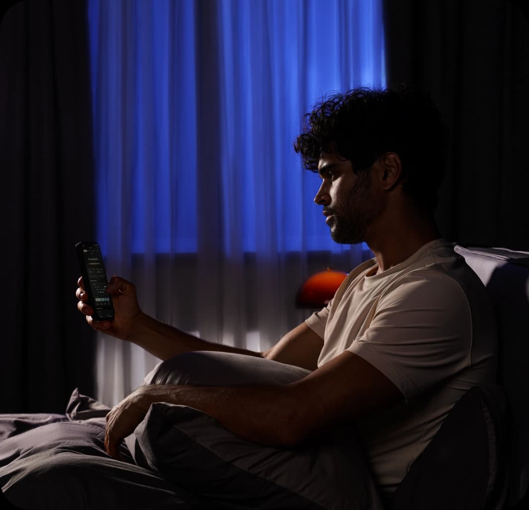 Person using sleep tracking device in bedroom with blue ambient lighting