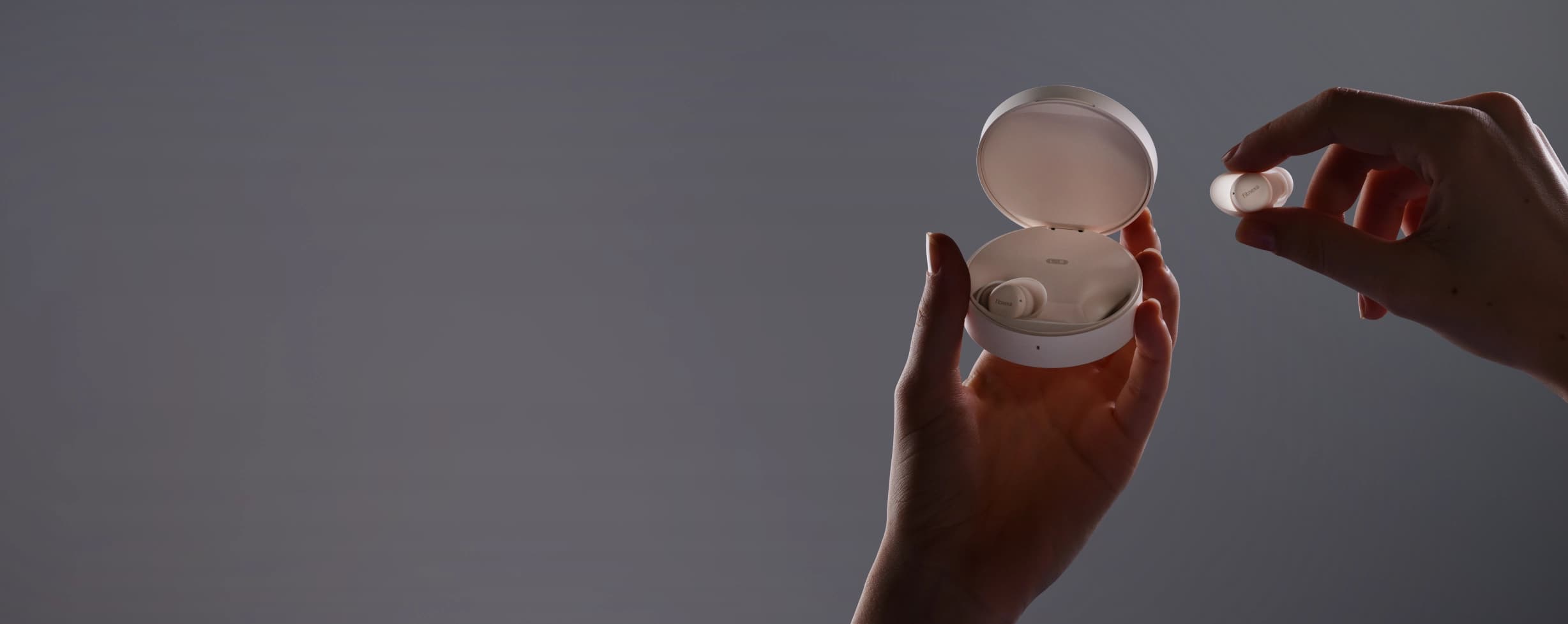 Hands holding Fitnexa charging case and earbud